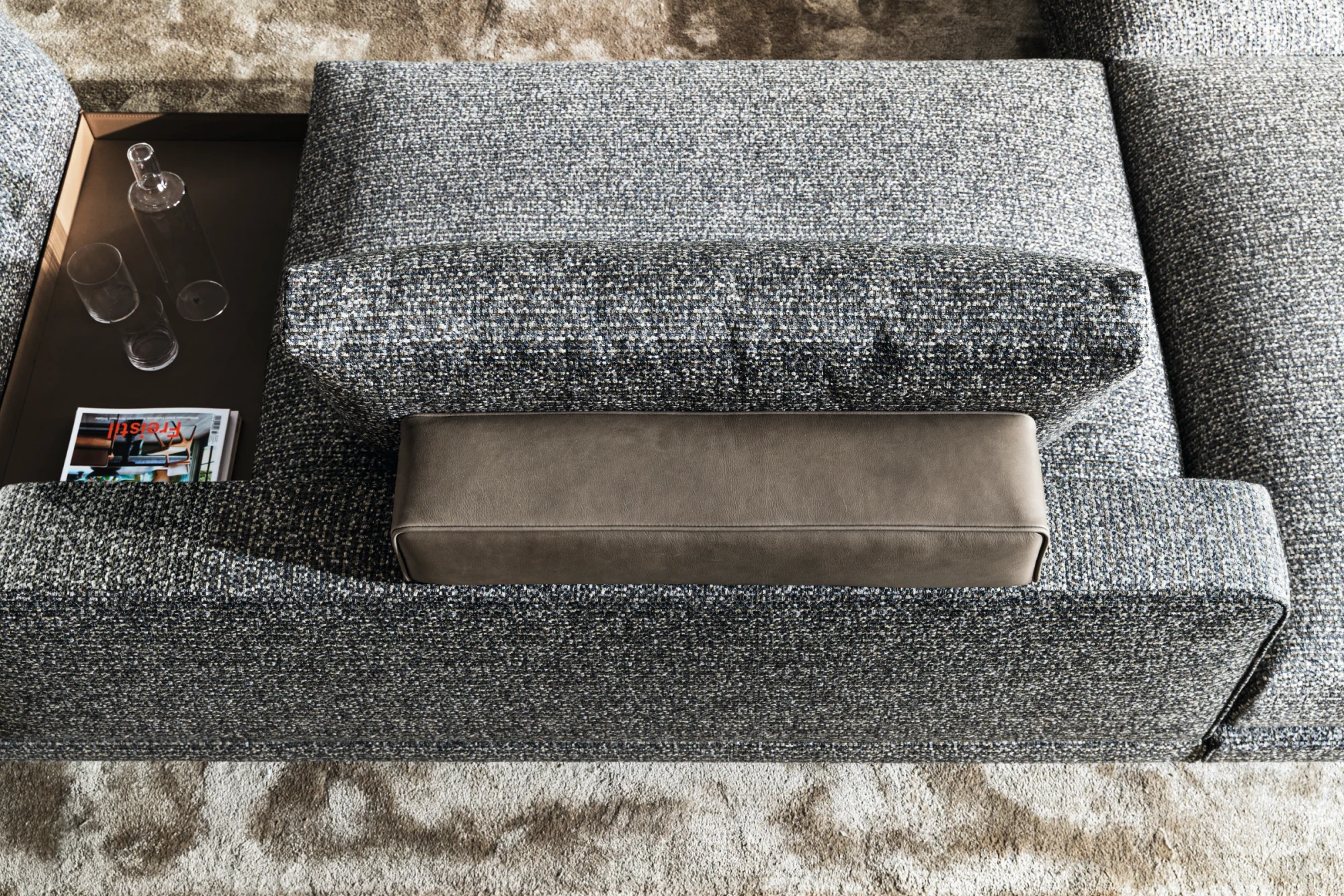 Overhead close view of a grey sofa with a headrest, back cushions and a trinket tray