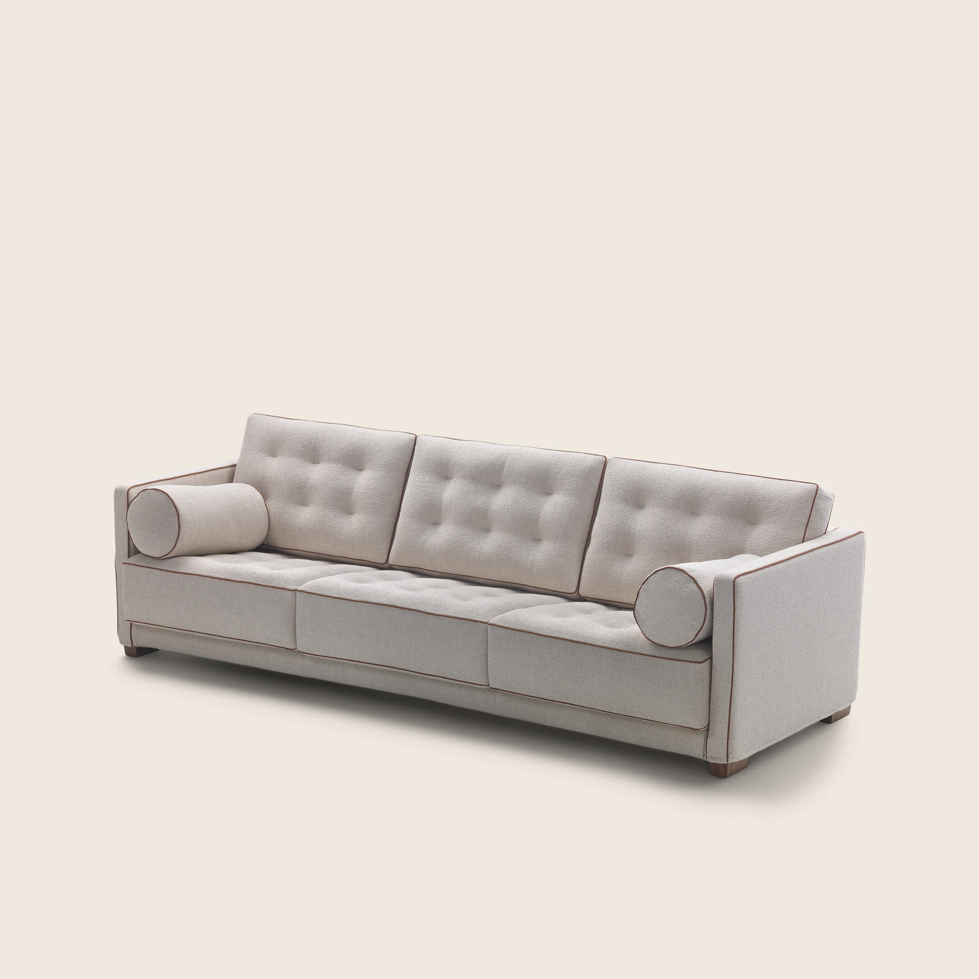 Three-quarter view of the Le Canapè sofa with round bolsters and stitched cushions