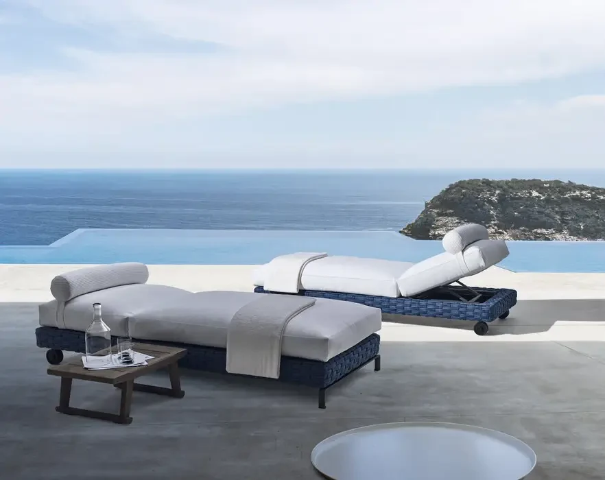 Due lettini Ray Outdoor Fabric accanto a una piscina con il mare sullo sfondo
