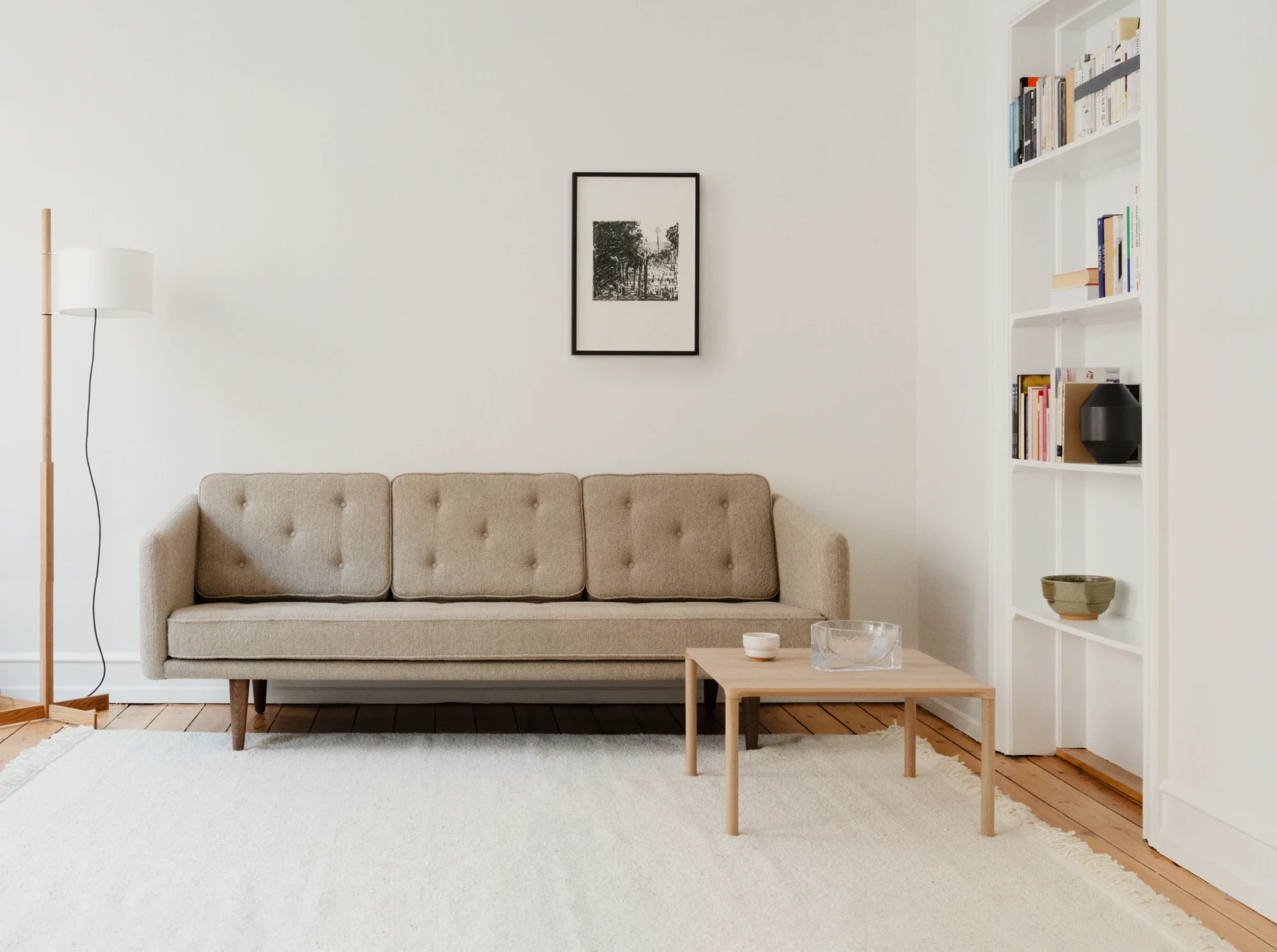 A sofa with buttoned cushions in a bright room with a framed picture on the wall