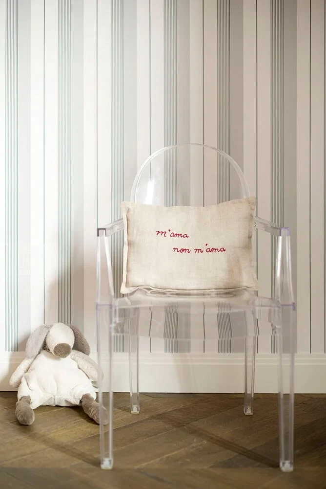 A transparent armchair with a cushion and a soft toy beside it
