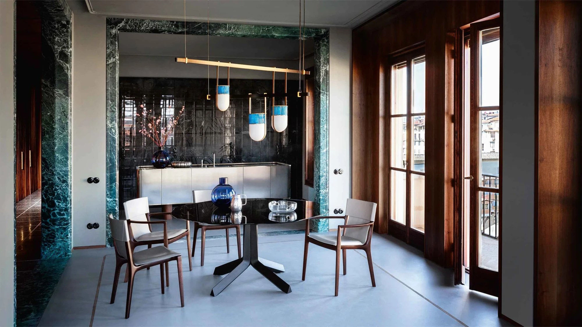 Round table with a three-armed base and chairs around it in a room with pendant lights