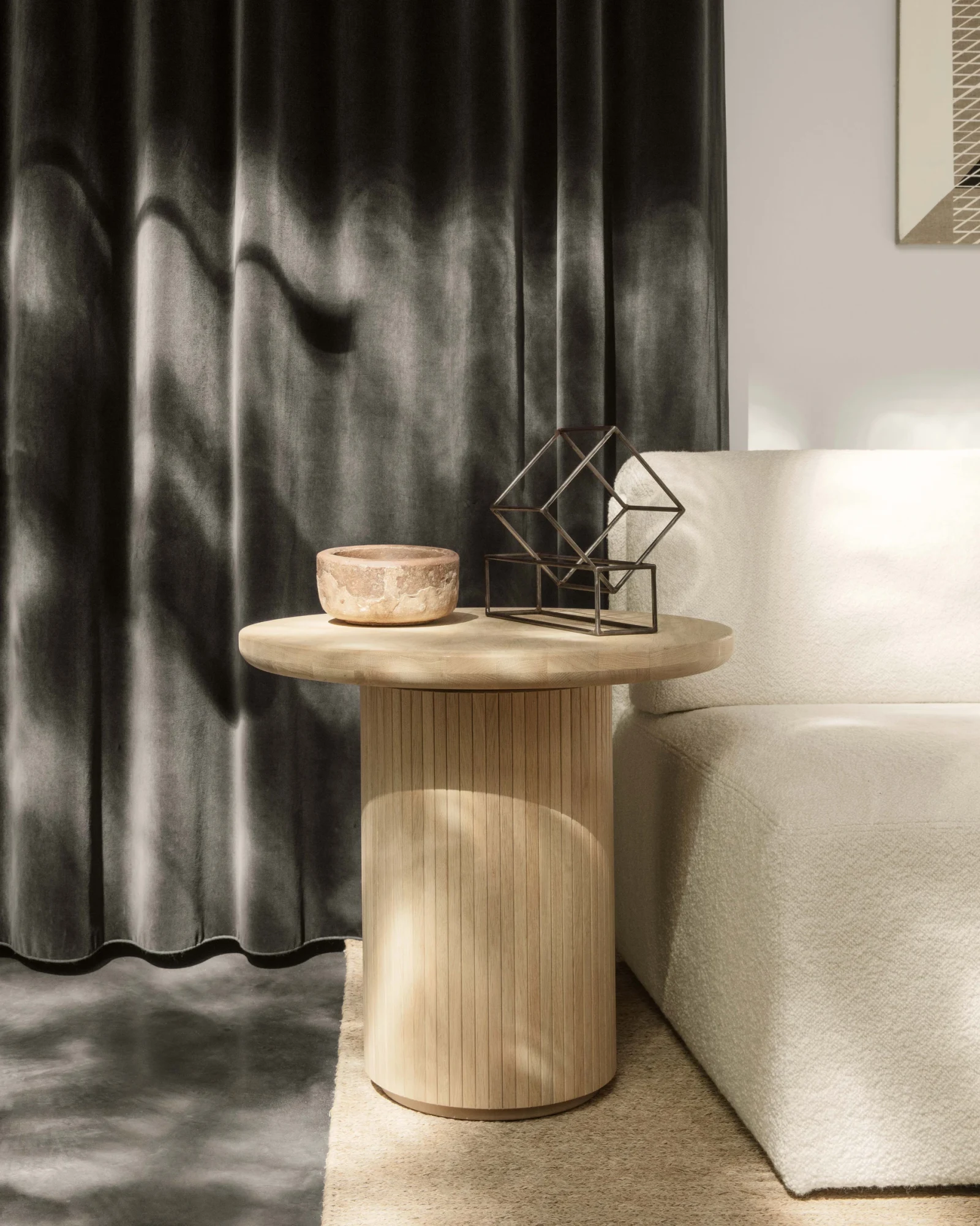 Round table with a pale top beside a sofa, with a bowl and an object on it