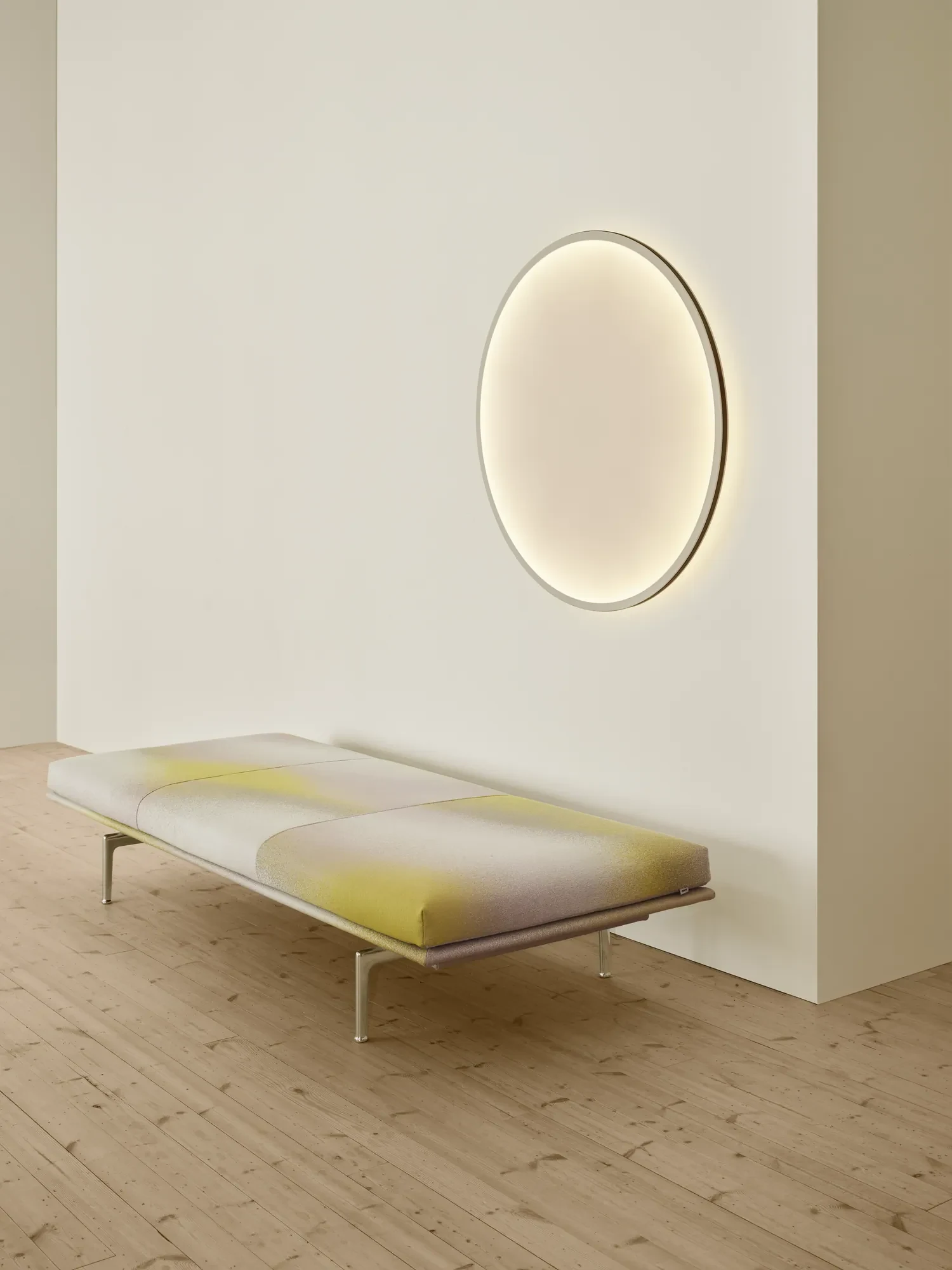 Outline Daybed below a round wall lamp in a plain room